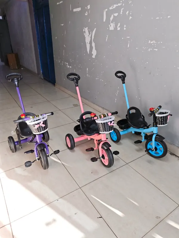 The purple, peach and blue push tricycles side by side