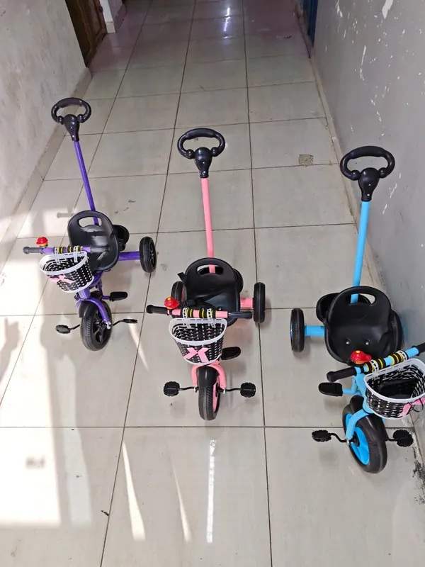 Purple, peach and blue push tricycles seen from the front