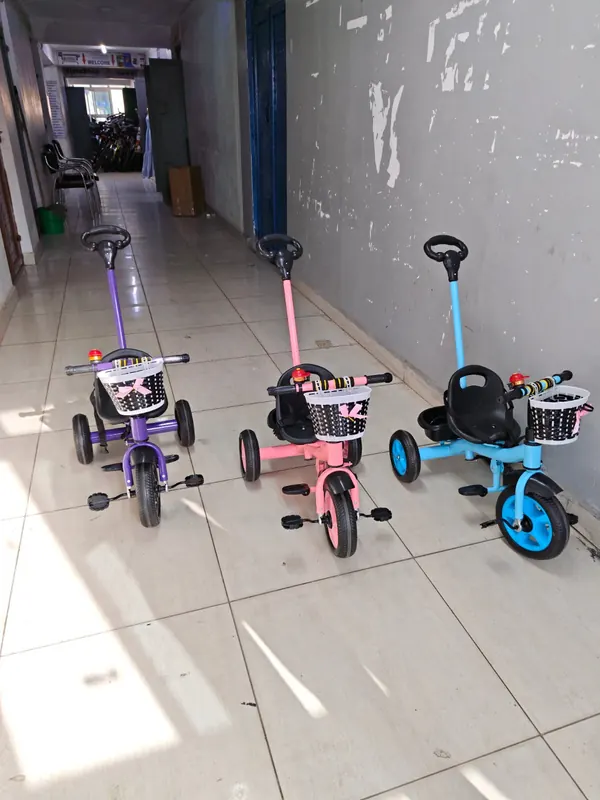 The three push tricycles lined up in a corridor, seen from the side